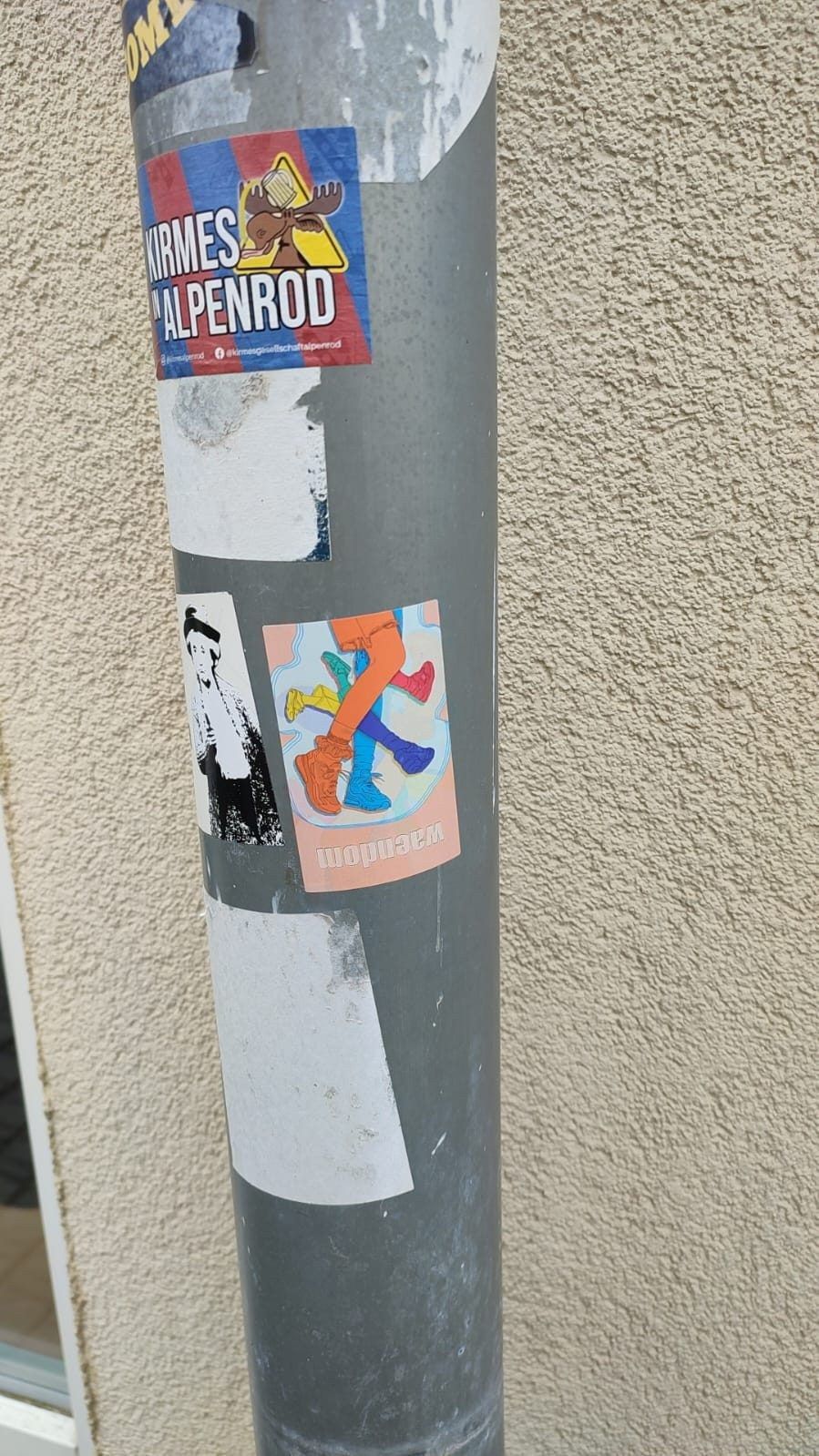 A waendom sticker on a lamppost, among other stickers