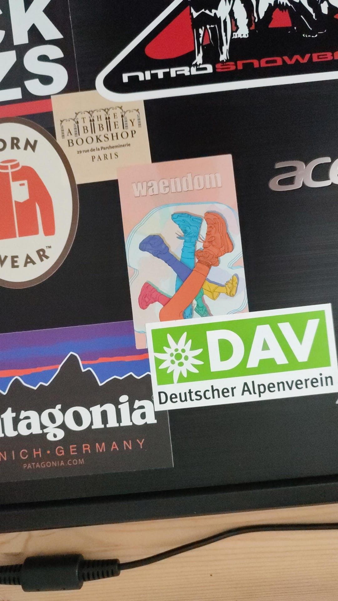 A waendom sticker on a laptop lid alongside other stickers